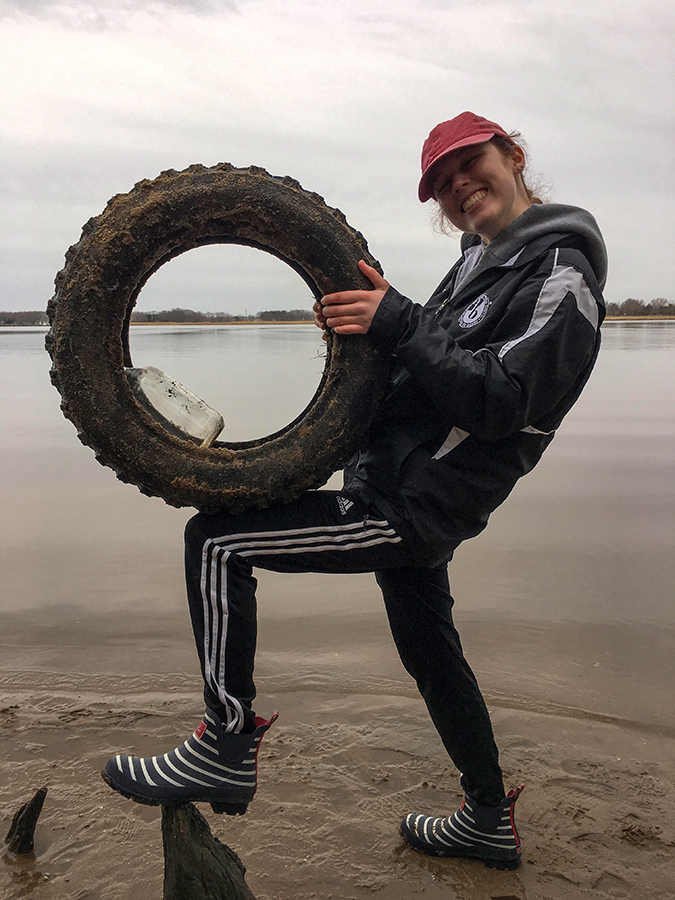 A student in Art in the Anthropocens with a tire found on a Chesapeake beach