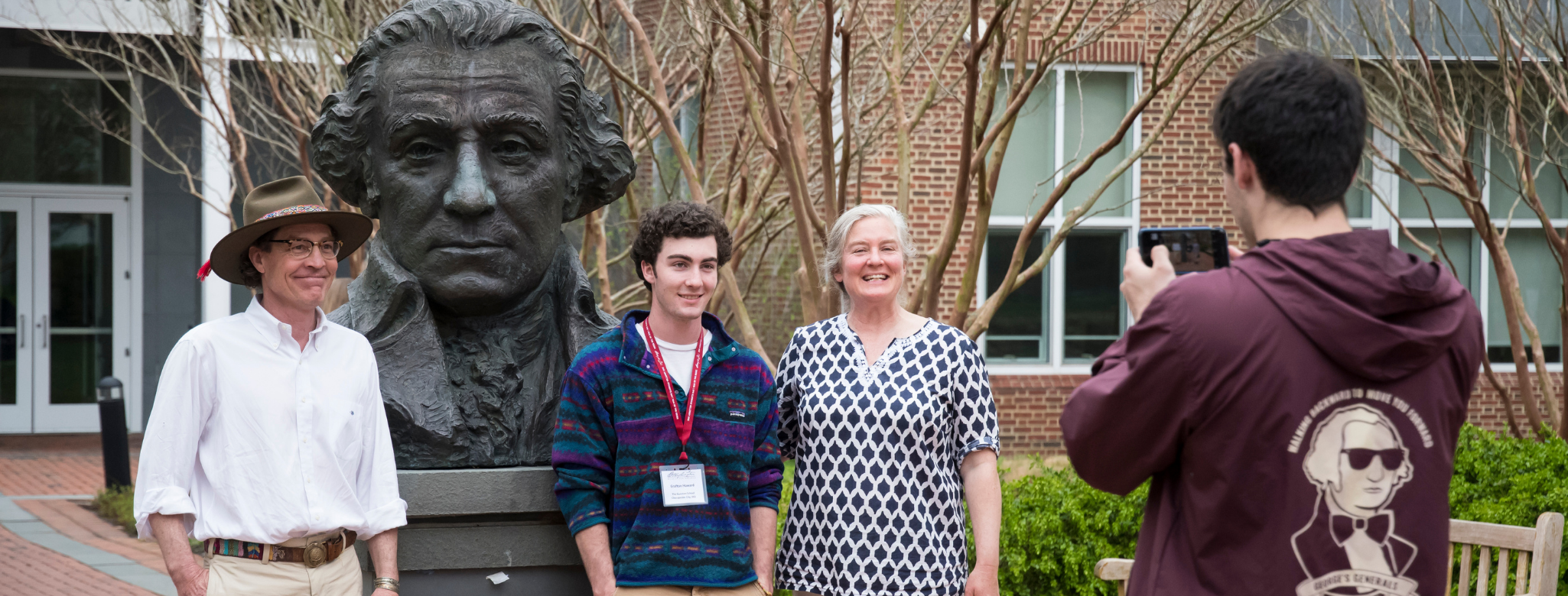 parents and child posing with the george washington statue at admitted students day