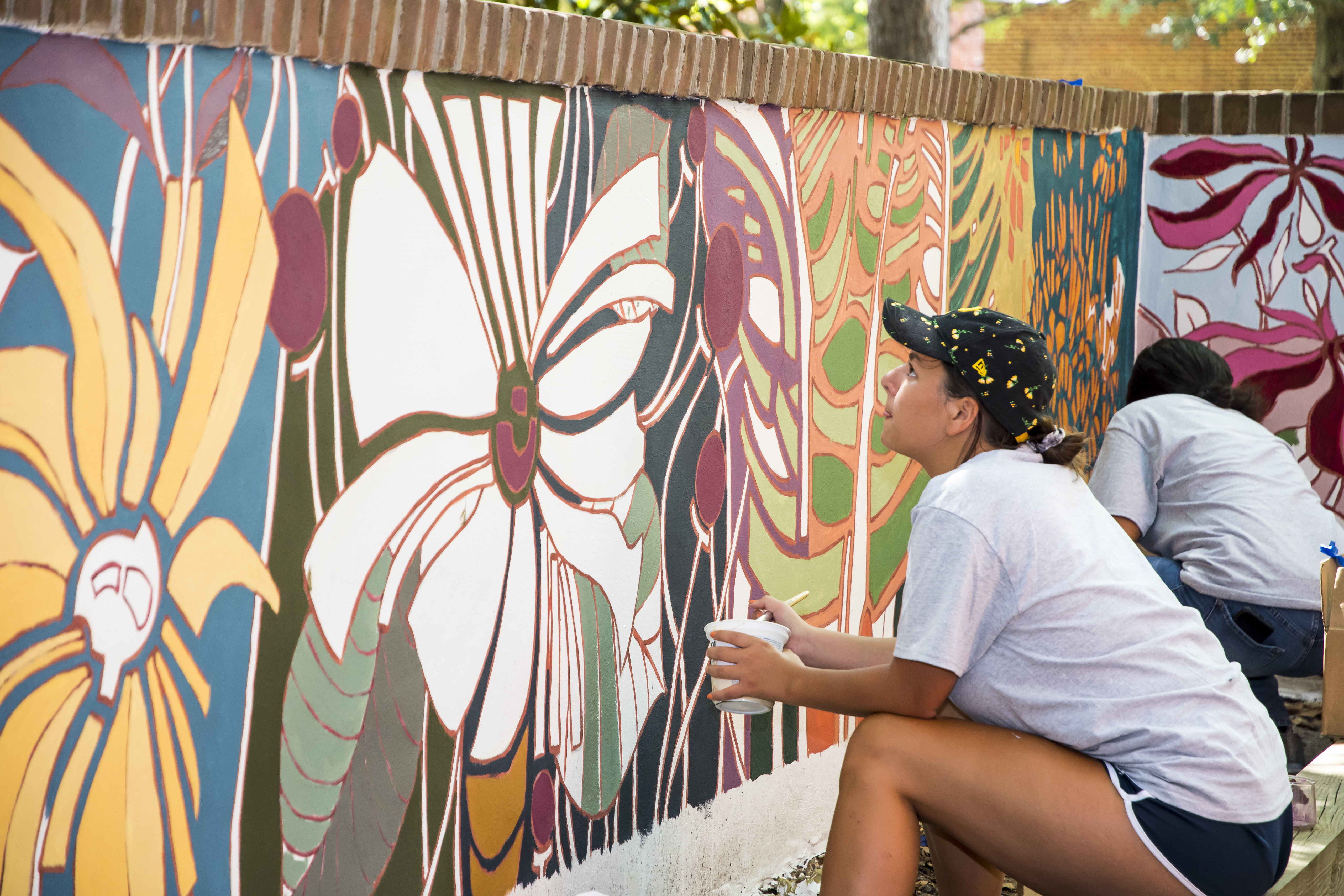 Student sitting in front of a mural.