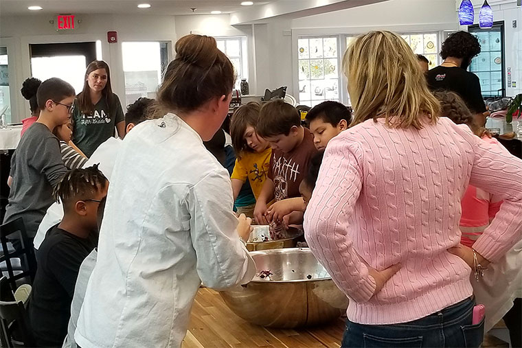 Students collaborate to mix chopped vegetables into sauerkraut.