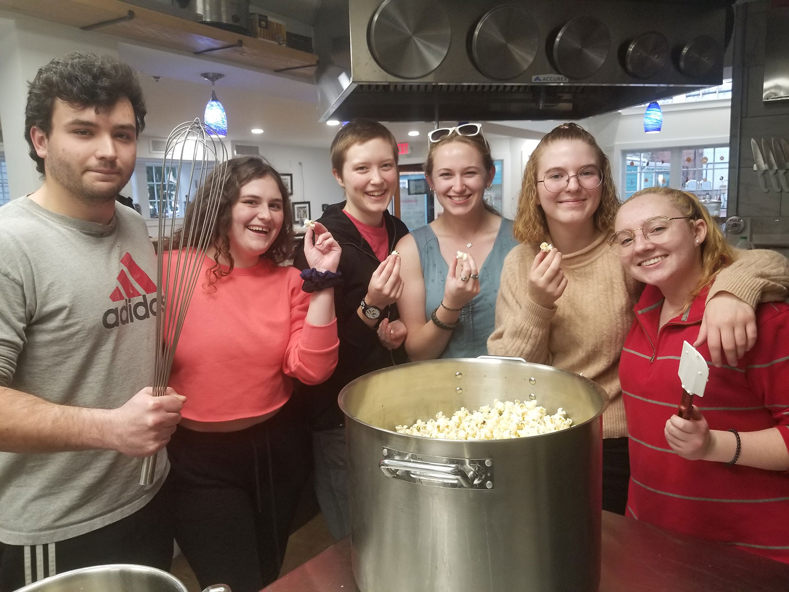 Six students standing around a large pot of popcorn