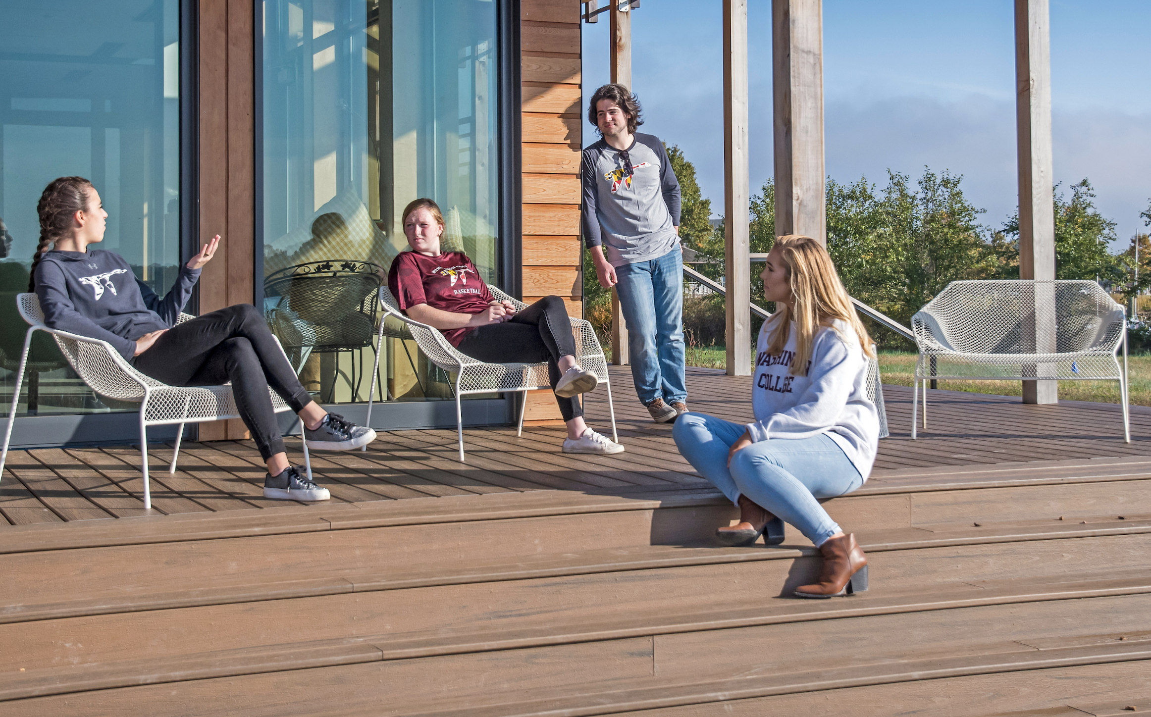 Washington College students sit on the deck at the boathouse having a conversation