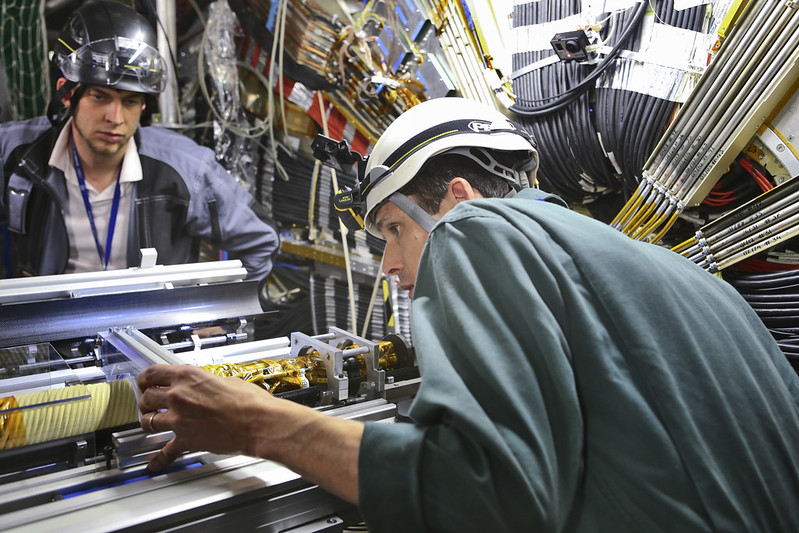 Physicists install a new component in ATLAS experiment equipment. Photo credit: CERN