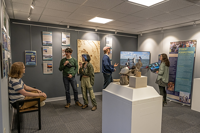 Students with work in the Chesapeake Semester exhibit talk in the MuSE: A Community Museum space as installation is completed.