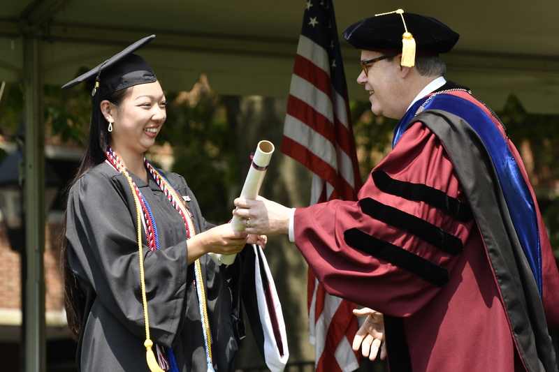 Sammy Segeda accepts her diploma from President Mike Sosulski while crossing the stage at the 2023 Commencement ceremony.