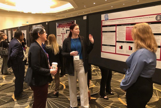 Sylvia Johnson '24 explains her research at a poster session to a conference attendee