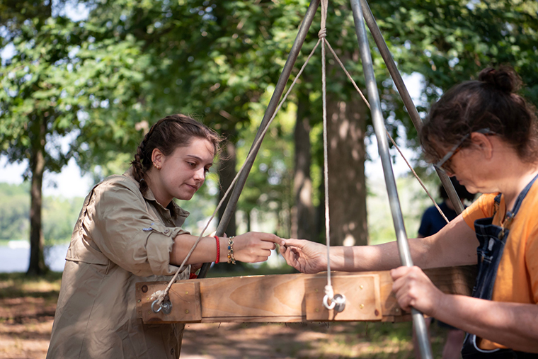 A volunteer passes a possible find to a Washington College archaeology student for help identifying it.