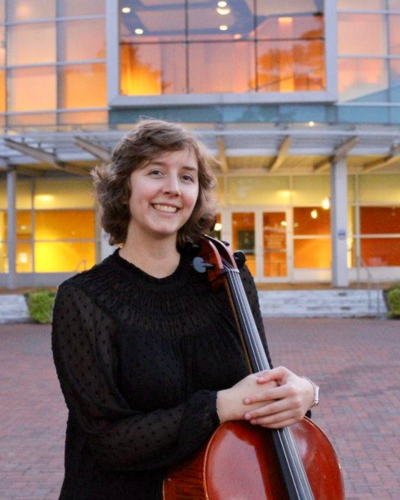 Sarah Poirier holds her cello in front of the Gibson Center for the Arts