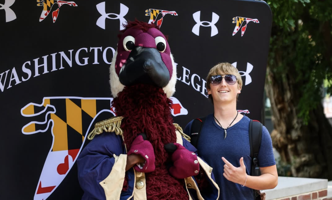 A student poses for a photo with Gus the Goose
