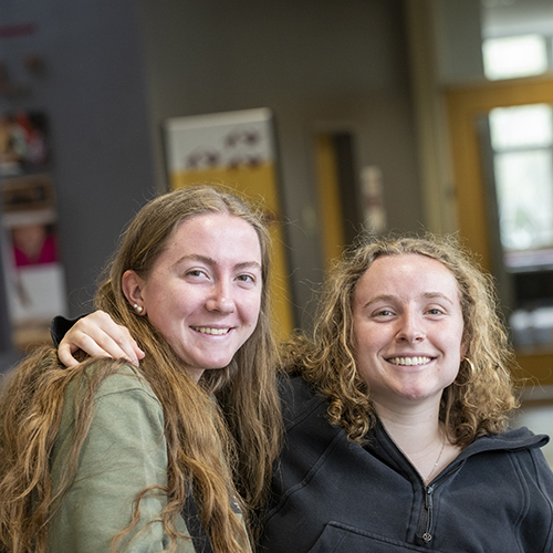 Two students smile for the camera