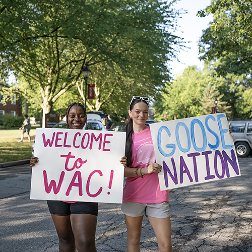 Peer mentors welcome students to campus with signs