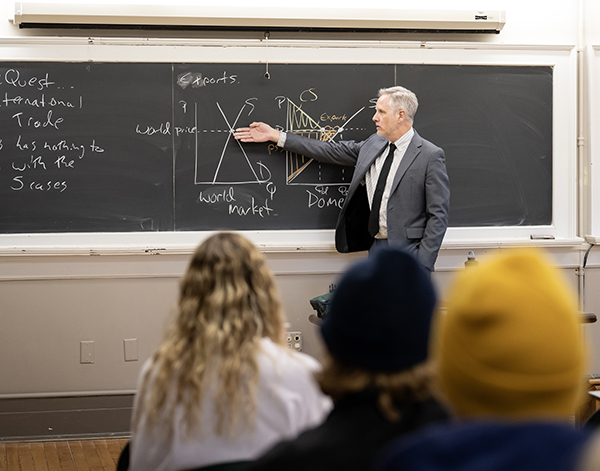 economics professor Brian Scott points to a graph on a blackboard