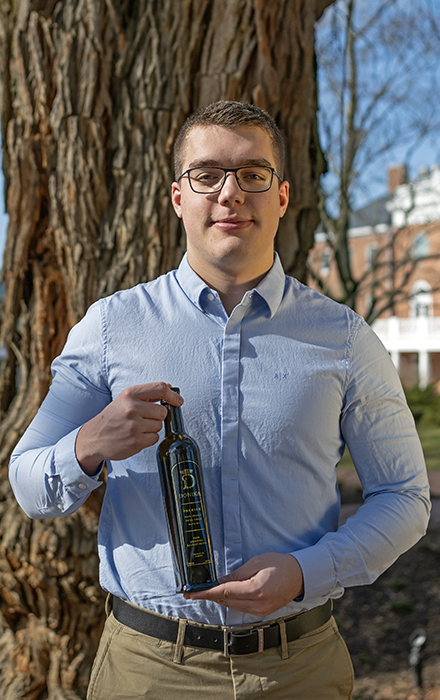 a Washington student with a bottle of the olive oil they sell in their start up