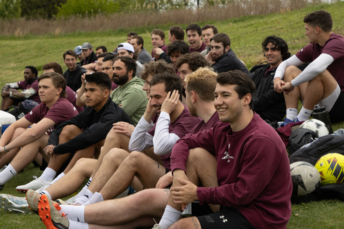 male soccer alumni sitting on sidelines