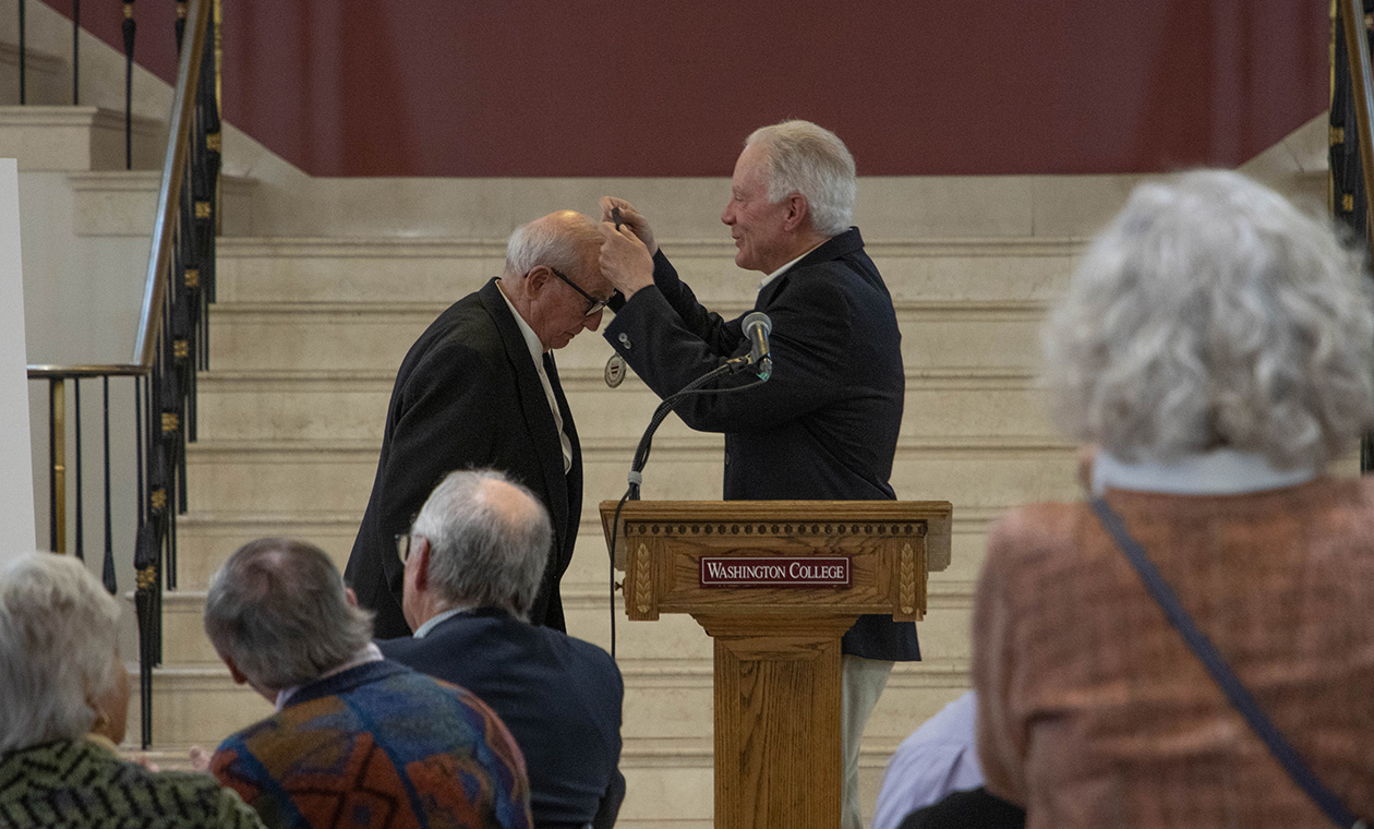 An alum receives an award from another at the Older and Wiser Alumni Dinner