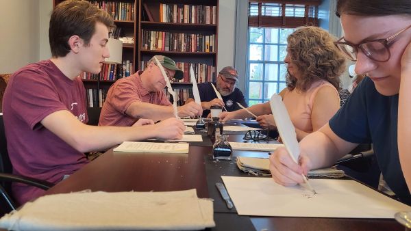people writing on table with quill and ink