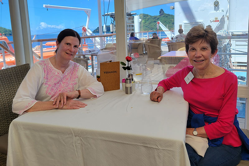 Two ladies sitting at a table, smiling for the camera