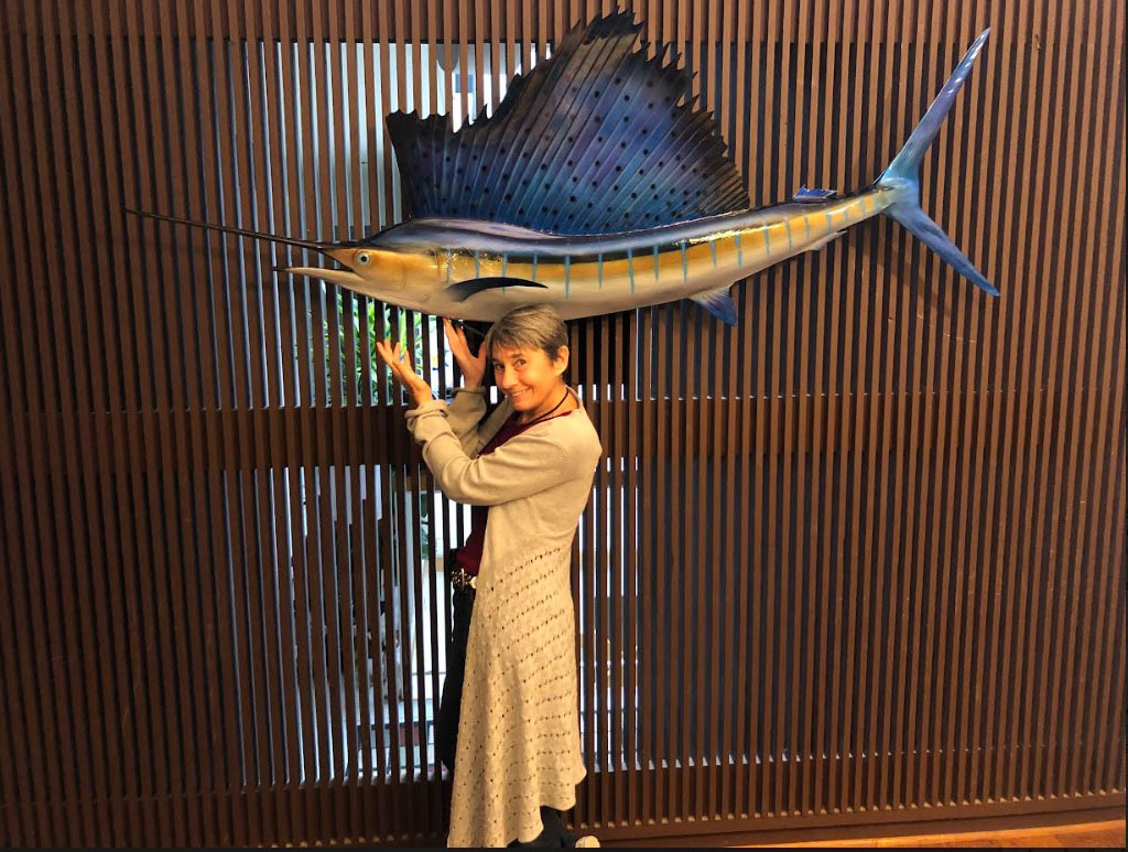 lady posing below mounted swordfish