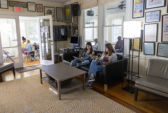 Students work on their laptops sitting on a couch in the Literary House