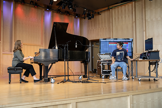 A student records a pianist on stage