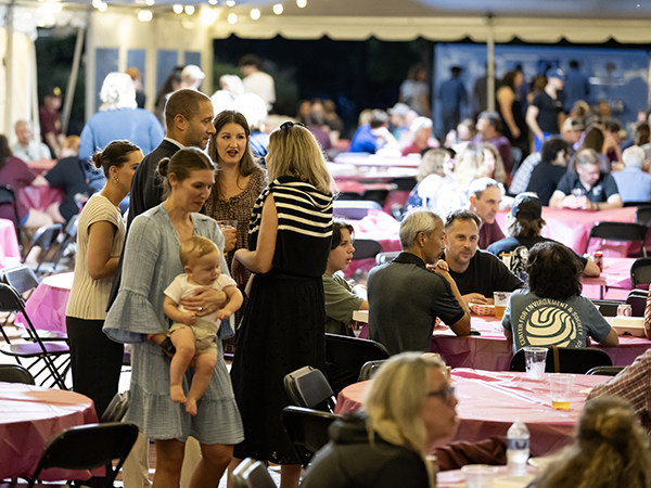 People socialize under the tent on Martha Washington Square with a food truck in the background