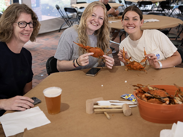 Students hold up steamed crabs