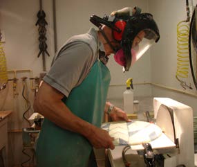 Person in apron, respirator and face shield working at bench