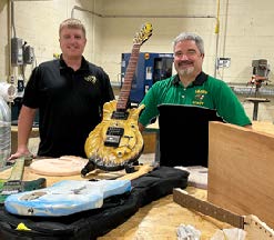 a student and instructor in a guitar-making workshop
