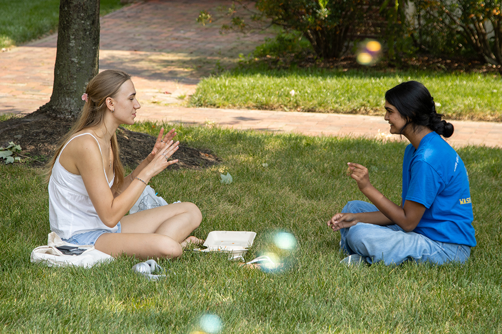 students sitting in the grass blowing bubbles 