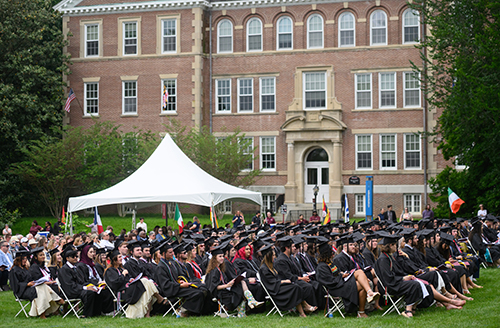 Students in the Class of 2024 sitting at their Commencement Ceremony, Smith Hall behind them