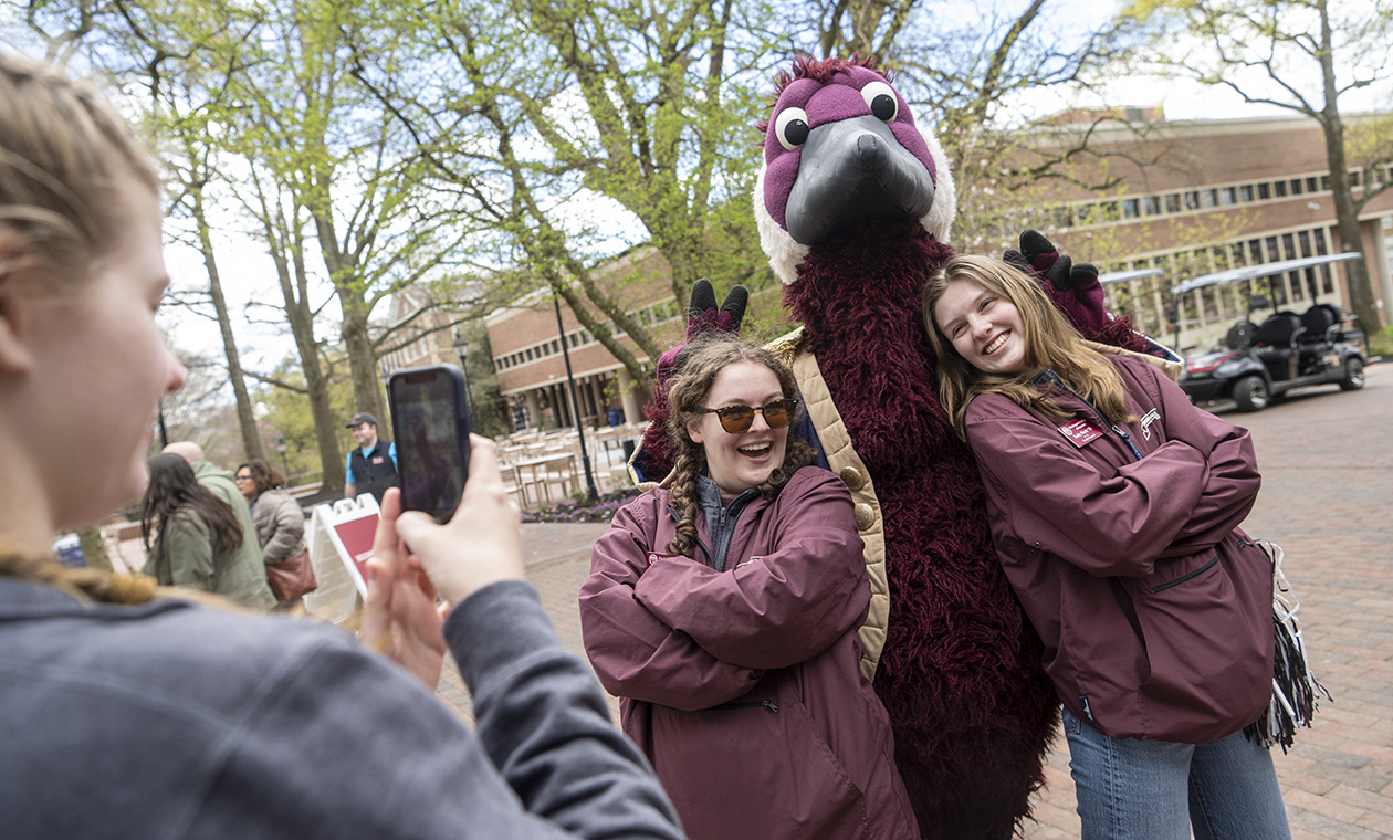 Gus the Goose poses for a photo with two students