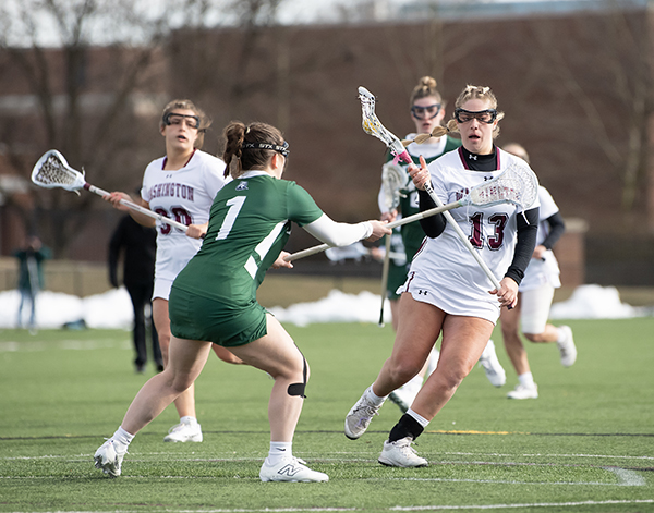 A Washington College women's lacrosse player moves past a defender