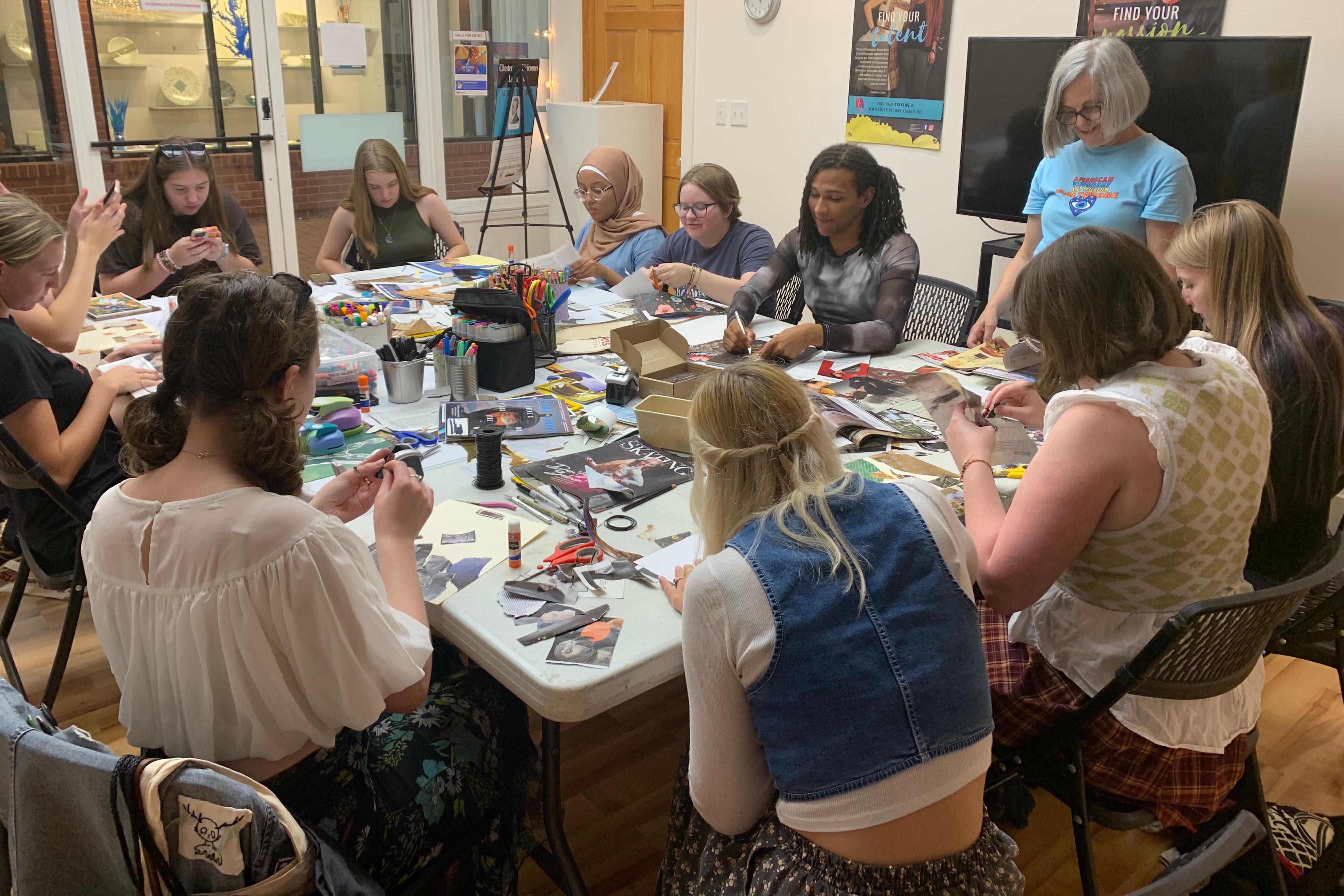 Students gathered around a large table working on a craft project