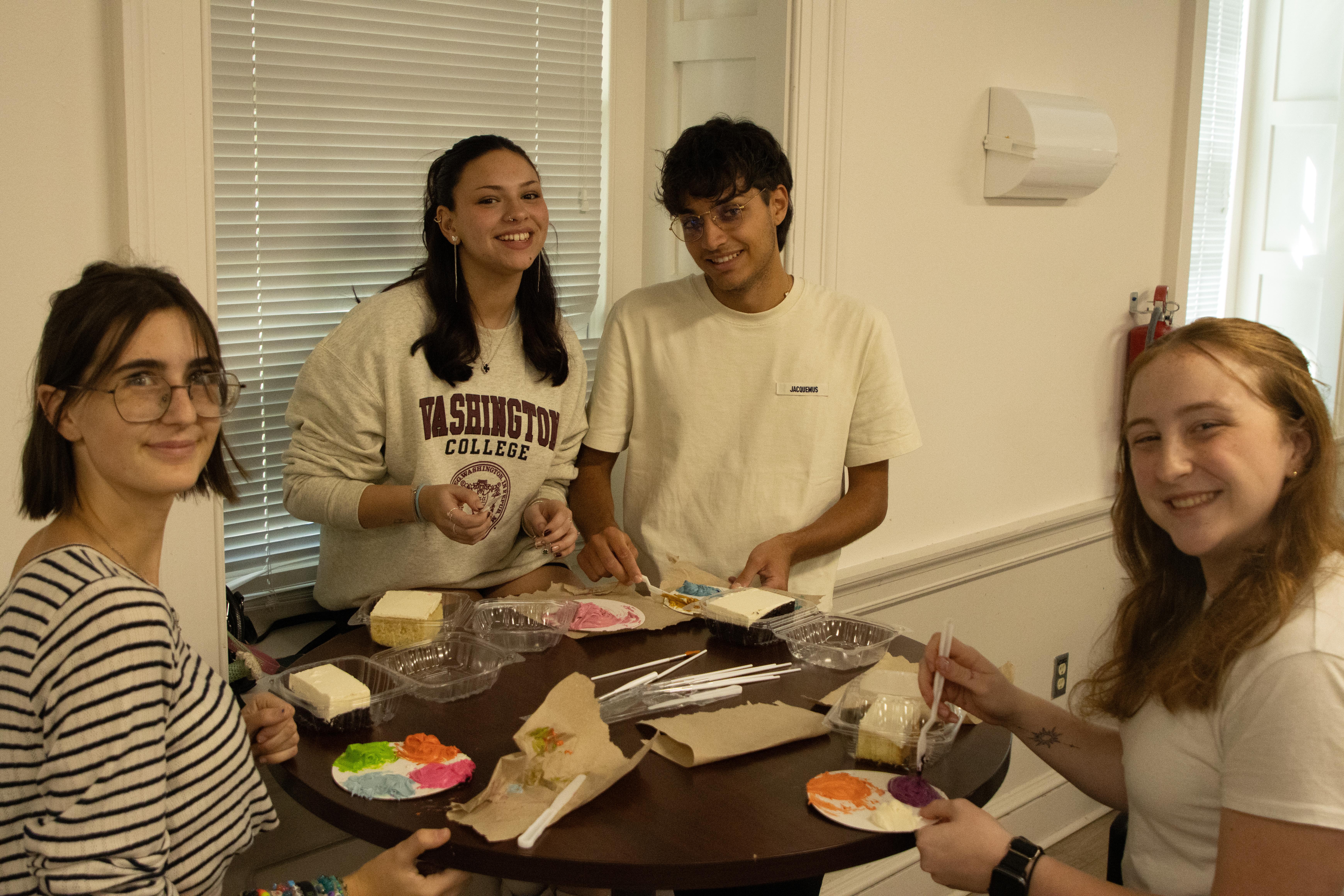 Candid photo of 4 students decorating slices of cake