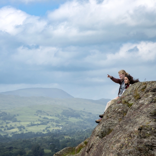 two students on a North Yorkshire, England mountain point off into the distance of rolling mountains and valleys