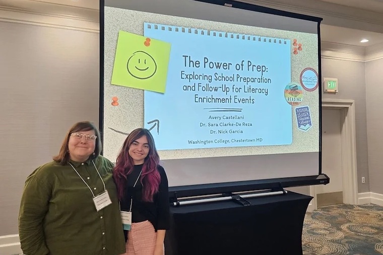 Professor Sara Clarke-De Reza and Avery Castellani '24 stand in front of their presentation on Busload of Books