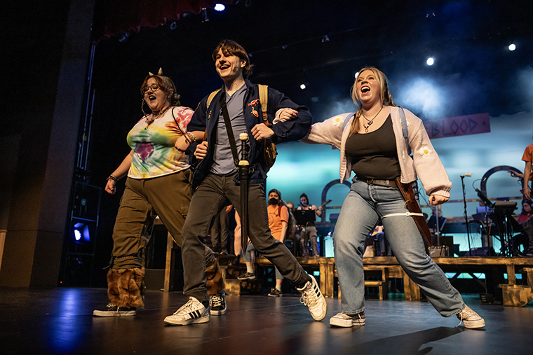 Three actors sing and walk across the stage during a production of The Lightning Thief: The Percy Jackson Musical