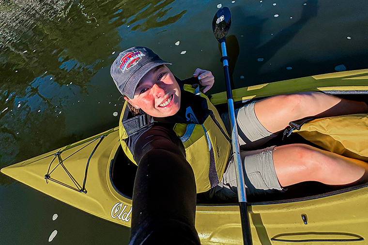 Anna McCabe sits on a kayak on the Sassafras River, a paddle across her lap.
