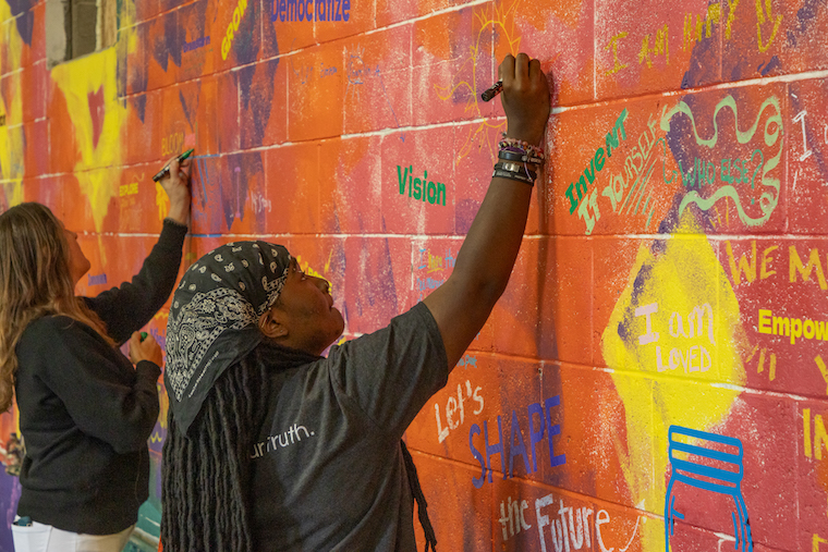Event attendees sign the mural in Washington College's Innocation Plant. 