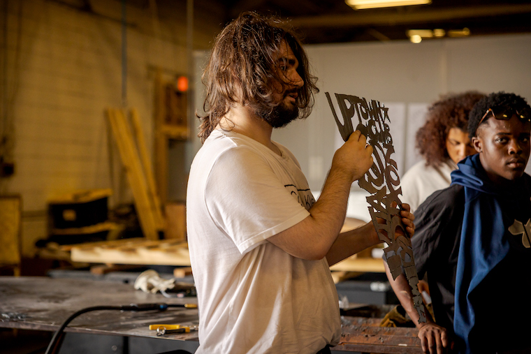 Jeremy Cress '27 shows off his metal table at the Washington College Innovation Plant. 