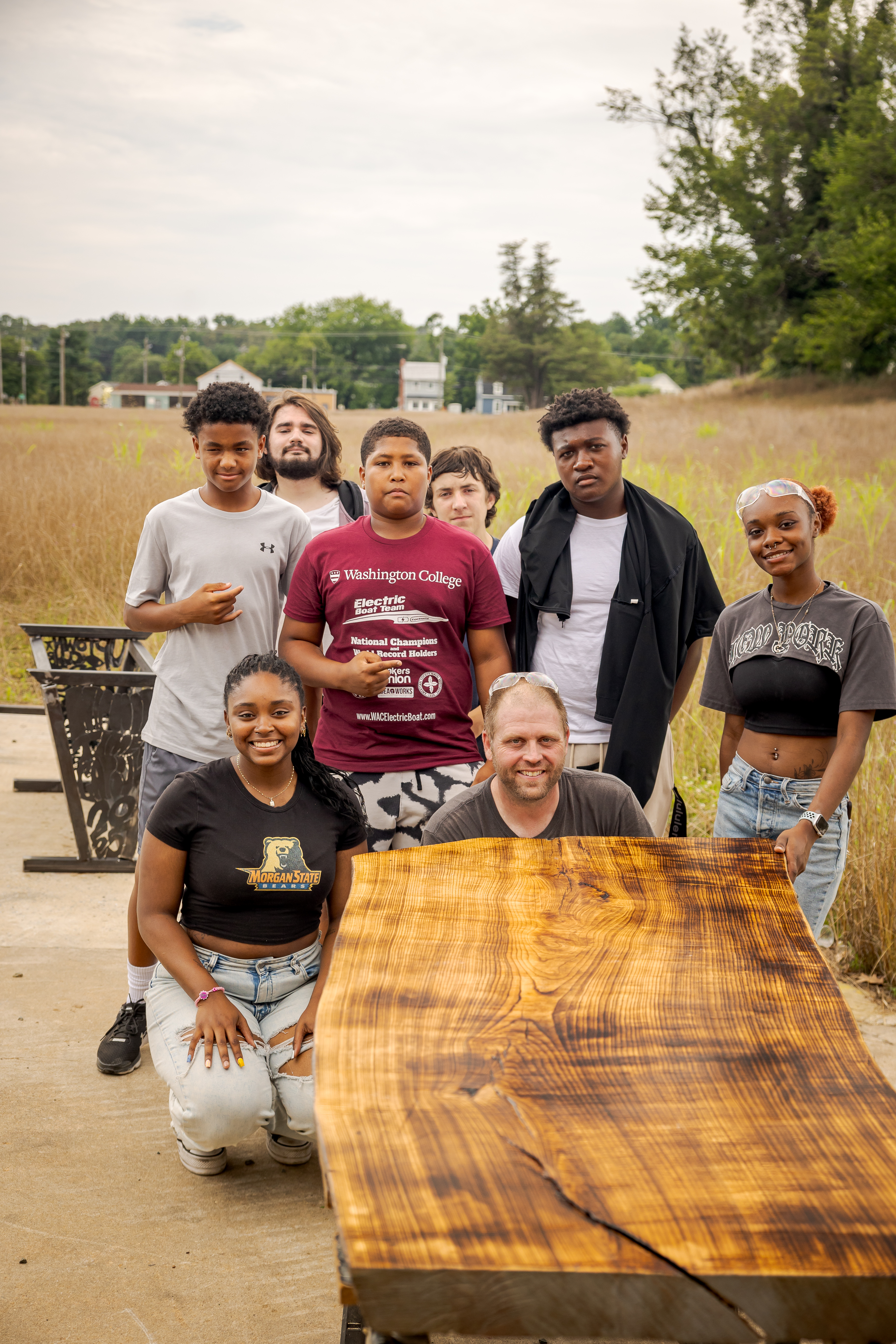 Jeremy Cress '27 with his team of high school and college interns, standing proudly beside their finalized conference table that will one day live at the renovated Innovation Plant.