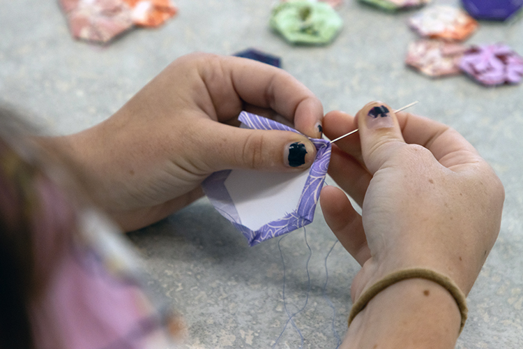 Imogene Nuss '28 sewing quilt pieces