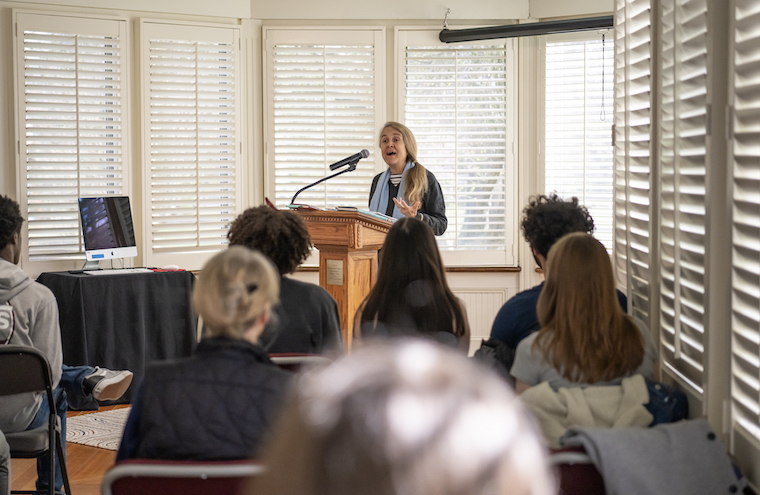 Naomi Shihab Nye speaks to a room full of students from a podium