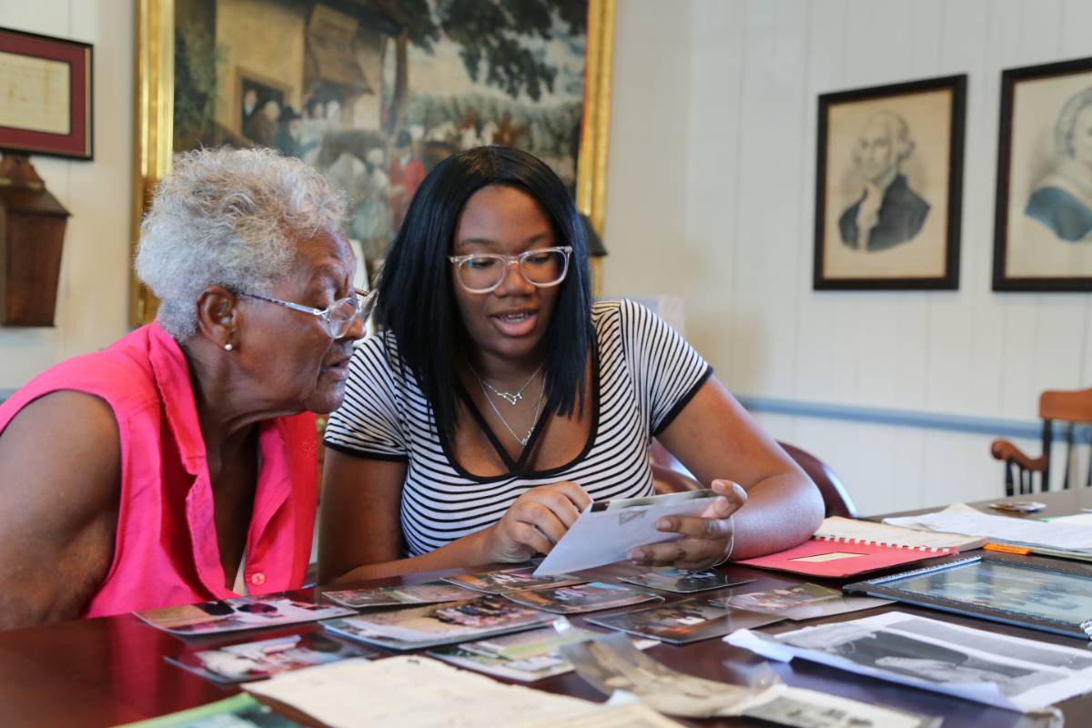 Paris Young, a political science major, works with Georgetown, Maryland, resident Irene Moore to document newspaper clippings and photos about a segregated one-room schoolhouse in Worton which Moore attended. 