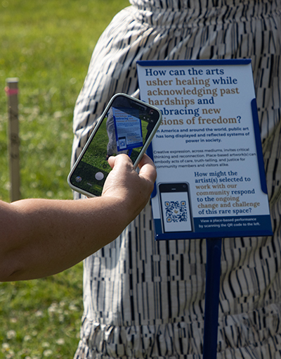 a smartphone reading a QR code on a sign on the Custom House lawn