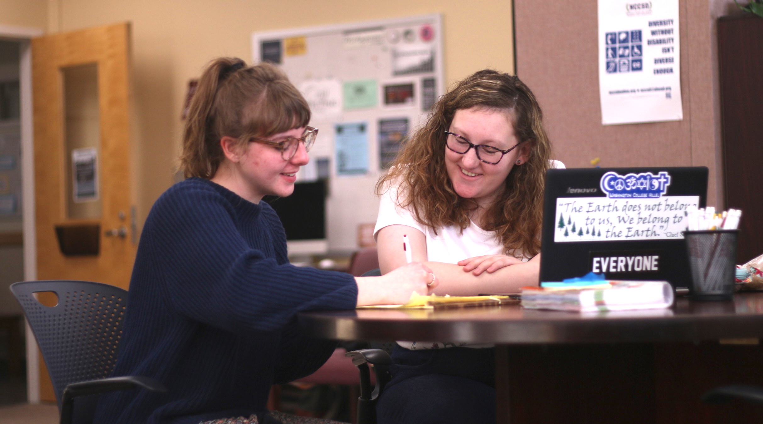Two female students working at the Writing Center, looking at a laptop