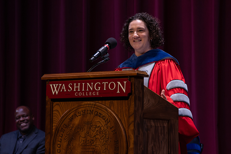 Professor Rachel Durso in academic regalia at a Washington College podium 