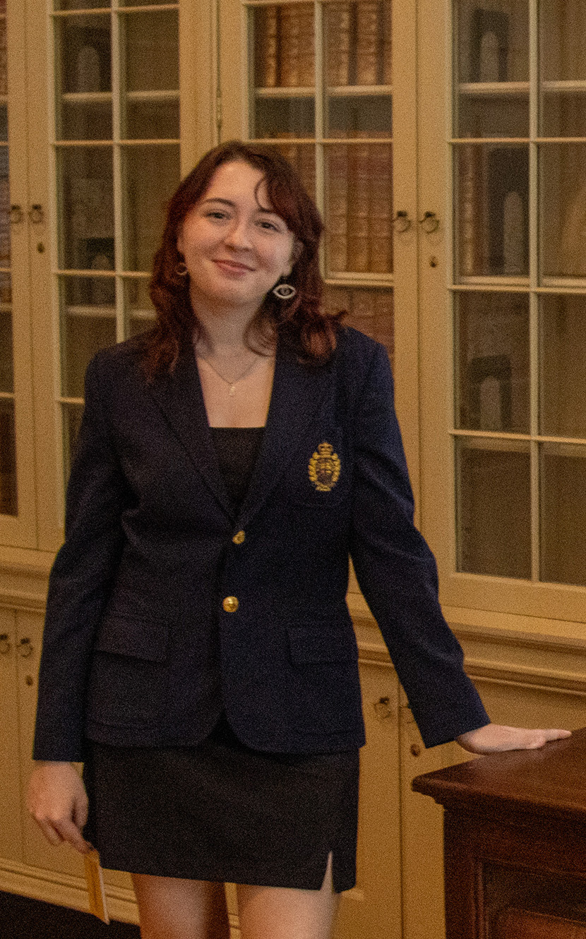 Nora Beebe '26 standing in front of a bookcase