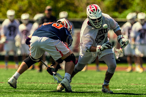 Skyler Clark, wearing a Washington College Men's Lacrosse uniform faces off against an opponent.