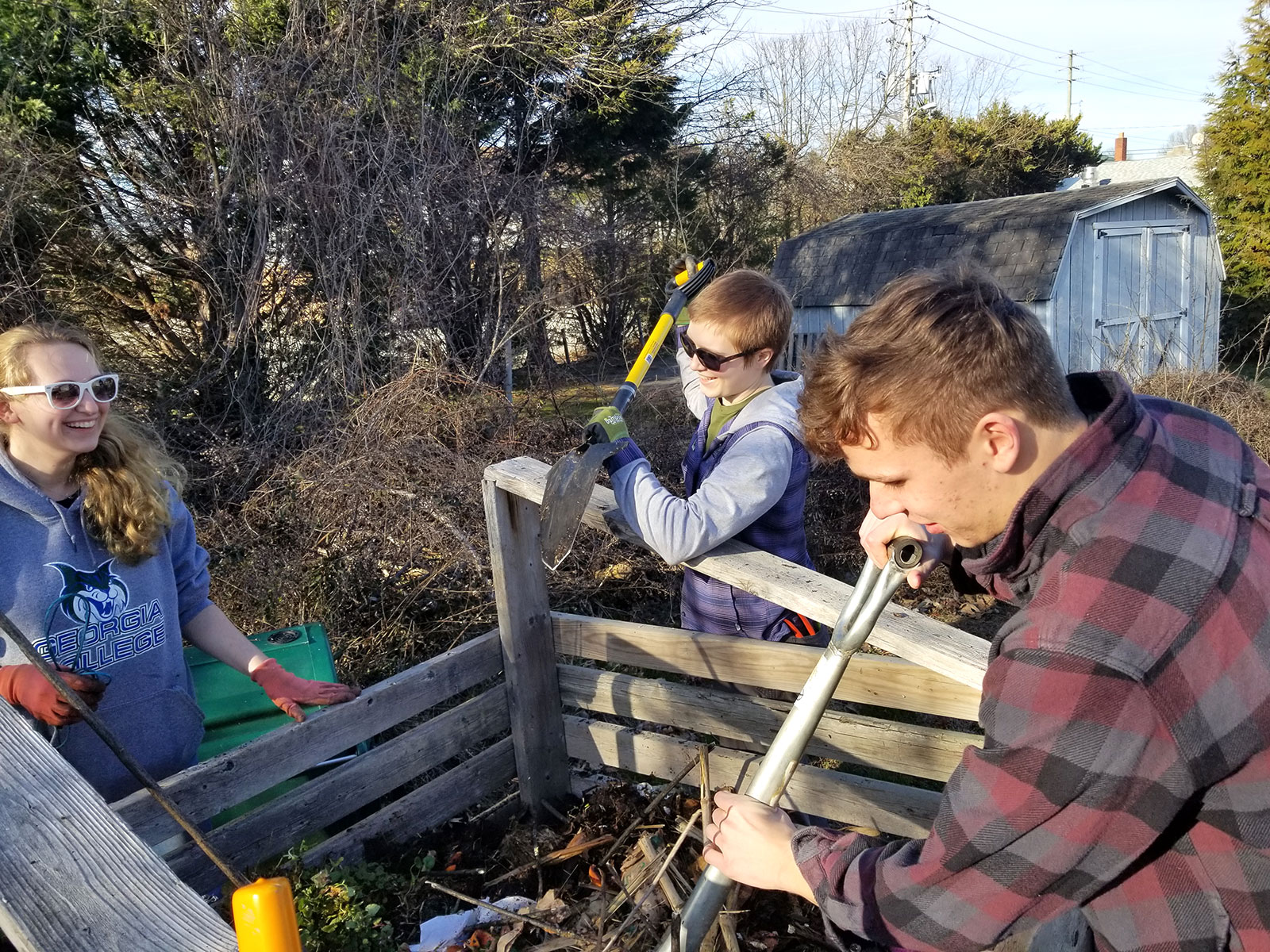 students aerate a compost bin in the campus garden